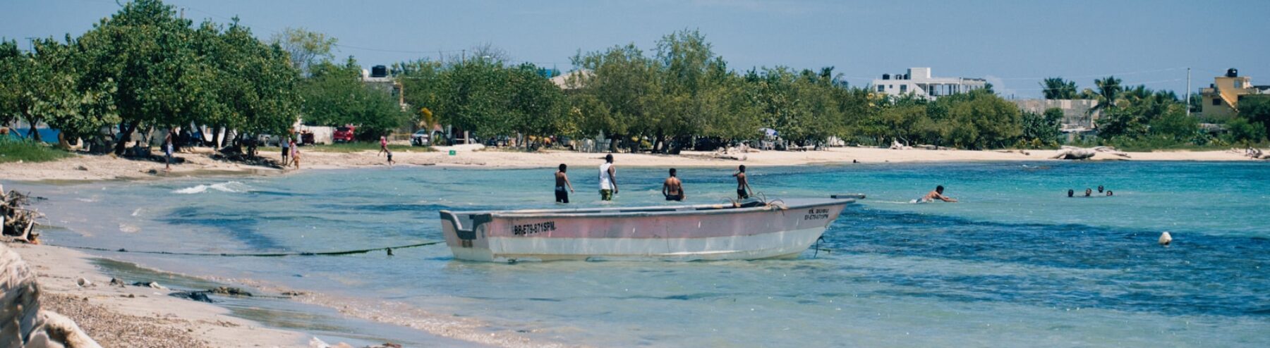 A long boat with people on board in turquoise water.